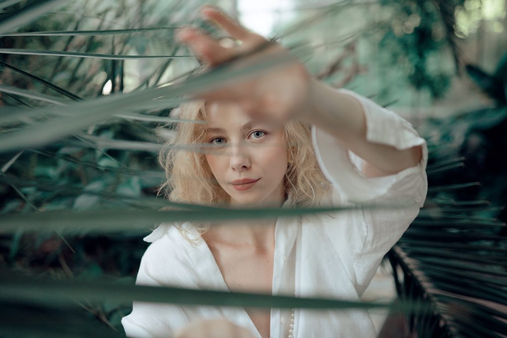 Stylish woman touching green plant leaf in garden