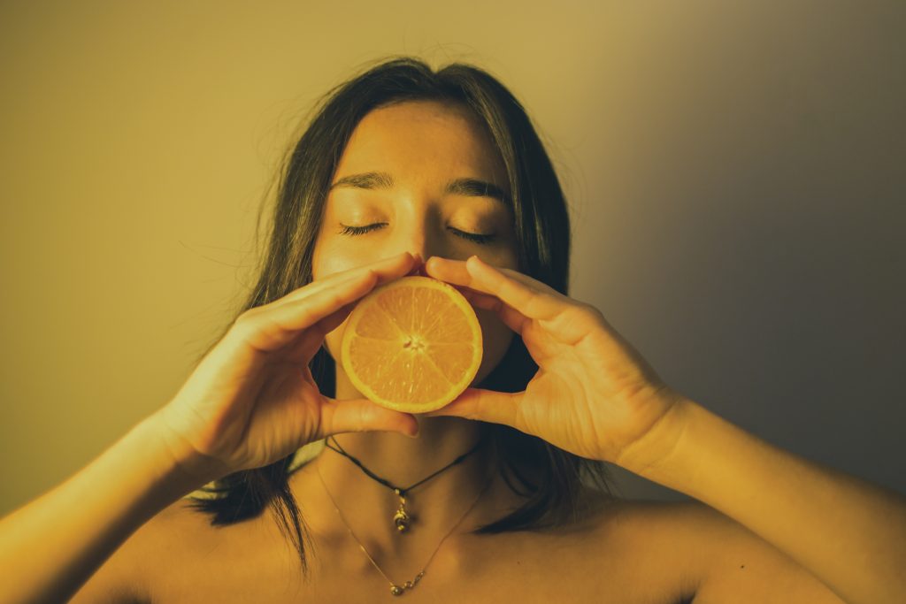 Attractive woman with eyes closed holding orange slice against lips